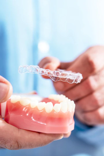 closeup-doctor-puts-transparent-aligners-teeth-artificial-jaw_114354-2523